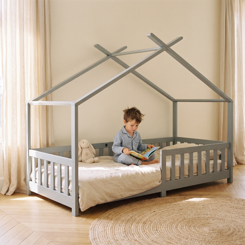 Lit cabane gris à barreaux avec un enfant